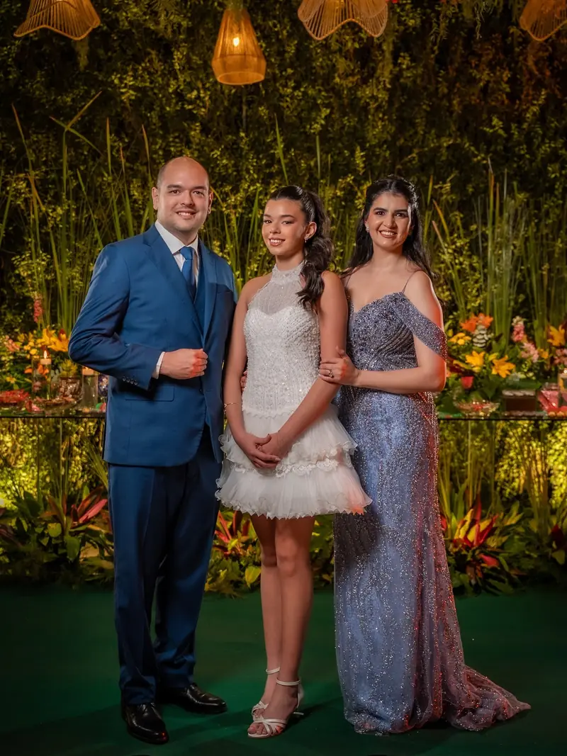 Quinceañera con su papá y su hermana en el jardín del salón