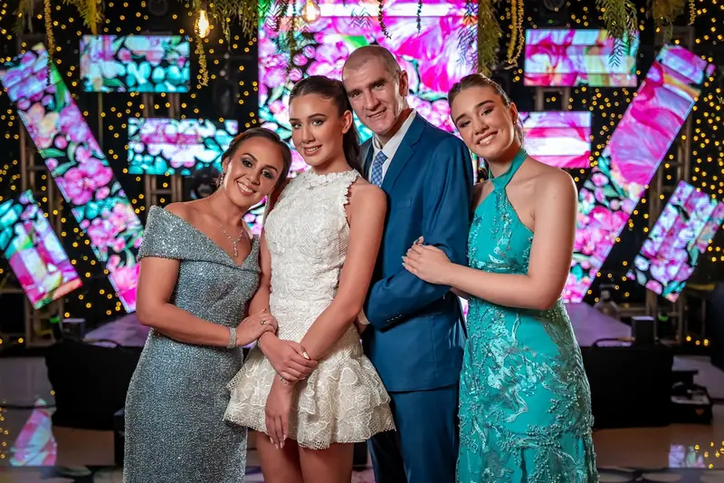 Quinceañera con su papá, su mamá y su hermana frente a las pantallas